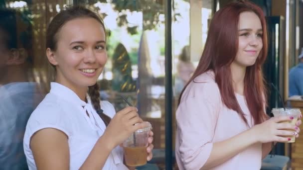 Dwie dziewczyny rozmawiają w kawiarnię na świeżym powietrzu. piją koktajle na ulicy. 4k, zwolnionym tempie fotografowania. — Wideo stockowe