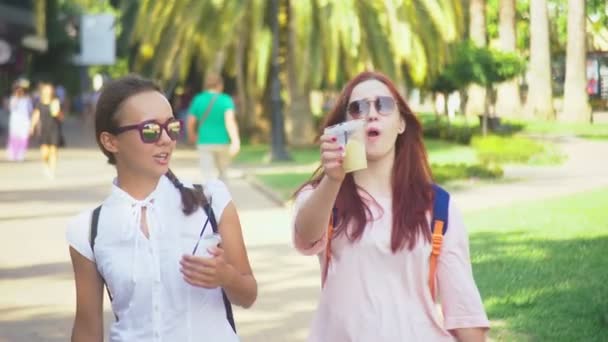 Två flickor prata och dricka drinkar medan du går utanför. 4k, Slowmotion-skytte. — Stockvideo