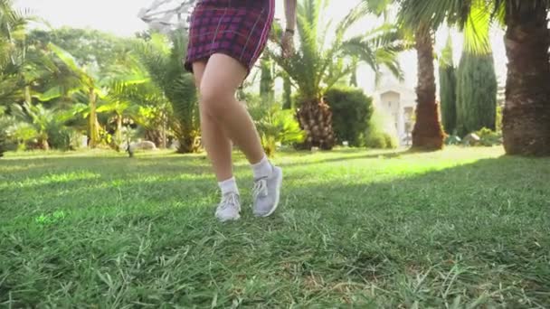 Jovem bela menina ruiva dançando no parque. mulher em uma mini saia dançando em um parque tropical em um fundo de palmas. 4k, câmera lenta — Vídeo de Stock