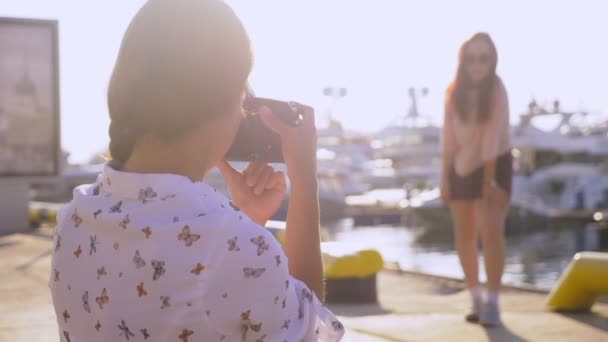 Professionele fotograaf, afbeeldingen in de zeehaven tegen de achtergrond van jachten, een vrouw op een knop drukt en praat met het model. 4k, slow-motion, — Stockvideo