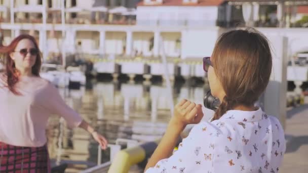 Профессиональный фотограф, фотографии в морском порту на фоне яхт, женщина нажимает кнопку и разговаривает с моделью. 4k, slow motion , — стоковое видео