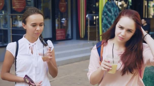 Dwie dziewczyny porozmawiać i wypić koktajl podczas chodzenia poza. 4k, zwolnionym tempie fotografowania. — Wideo stockowe