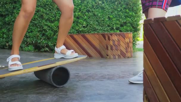 Kobiece nogi bliska. słoneczny letni dzień. Kobiety na pokładzie balance Board. Płyt Rocker-roller. owalne, drewniany taras balance Board. Wałek balance Board. 4k, zwolnionym tempie — Wideo stockowe