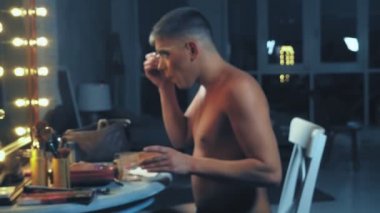 travesti-diva. Bir travesti kavramı. Adam-aktör bir kadına dönüşür. bir adam, yüzünde bir makyaj uygulanır. Aynanın önünde odaya. 4k, ağır çekim, steadicam çekim