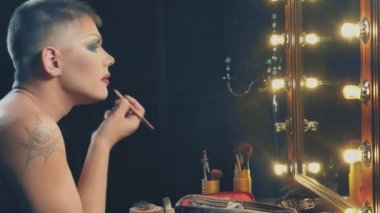 travesti-diva. Bir travesti kavramı. Adam-aktör bir kadına dönüşür. bir adam, yüzünde bir makyaj uygulanır. Aynanın önünde odaya. 4k, ağır çekim, steadicam çekim