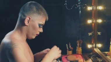 travesti-diva. Bir travesti kavramı. Adam-aktör bir kadına dönüşür. bir adam, yüzünde bir makyaj uygulanır. Aynanın önünde odaya. 4k, ağır çekim, steadicam çekim