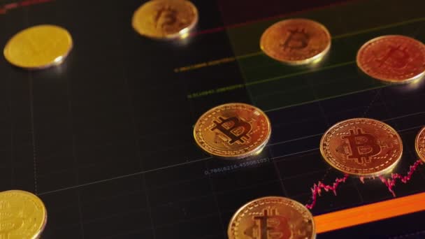 Monedas de oro, bitcoins en un fondo de brillantes gráficos financieros. Gráficos de negocios de cerca. Criptomoneda. Moneda virtual, grande 4k . — Vídeo de stock
