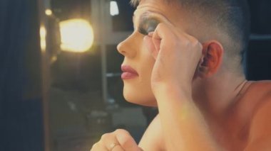 travesti-diva. Bir travesti kavramı. Adam-aktör bir kadına dönüşür. bir adam, yüzünde bir makyaj uygulanır. Aynanın önünde odaya. 4k, steadicam çekim