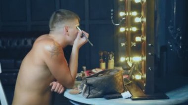 travesti-diva. Bir travesti kavramı. Adam-aktör bir kadına dönüşür. bir adam, yüzünde bir makyaj uygulanır. Aynanın önünde odaya. 4k, steadicam çekim
