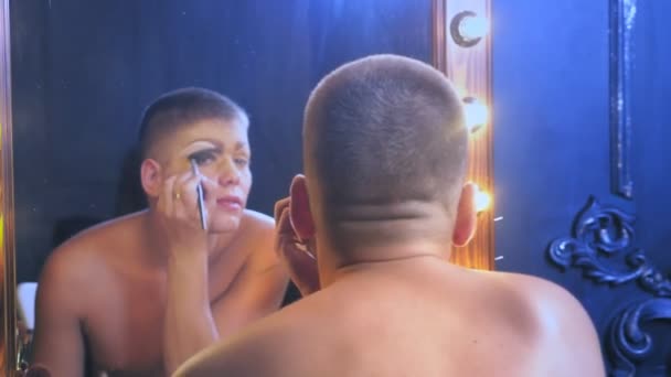 Parodia diva. Koncepcja transwestyta. Człowiek aktor zamienia się w kobietę. człowiek ma zastosowanie makijażu na twarzy. w sali przed lustrem. 4k, Strzelanie steadicam — Wideo stockowe