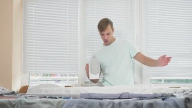 ev işi sırasında Gömlek Ütü kurulu dumanı tüten demir, kullanarak duran genç adam. 4k, ağır çekim