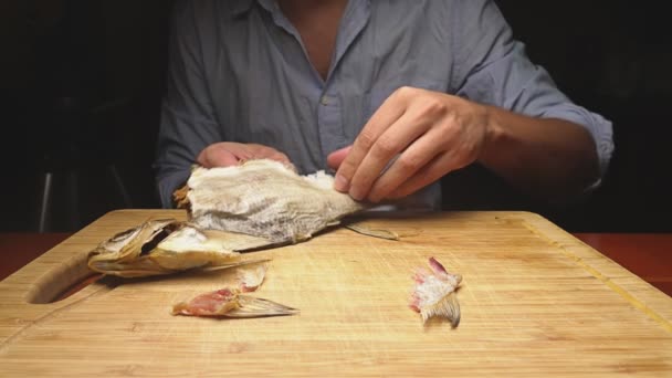 Primer plano. Las manos masculinas limpian el pescado seco salado. En la tabla de cortar. 4K cámara lenta — Vídeo de stock