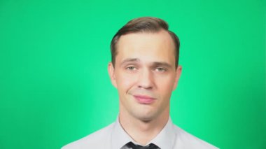 Bir madeni para bitcoin elinde tutan yakışıklı bir genç adam portresi. Yüzüne odaklan. yeşil arka plan, 4k, ağır çekim