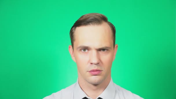 Porträt eines jungen, gut aussehenden Mannes, der mit einem Missverständnis in die Kamera blickt. grüner Hintergrund, Zeitlupe, 4k — Stockvideo