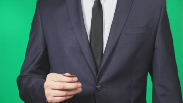 Man in suit and tie holding a coin bitcoin in his hand. He throws it. green background, 4k, slow motion — Stock Video