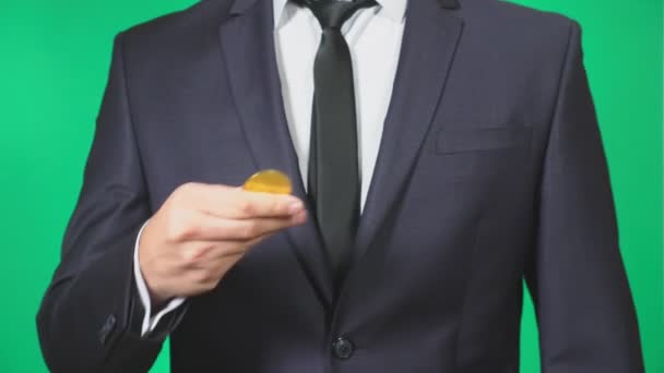 Takım elbise ve kravat bir sikke bitcoin elinde tutan adam. O atar. yeşil arka plan, 4k, ağır çekim — Stok video