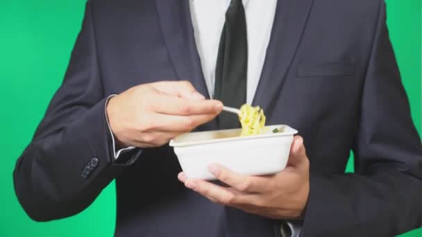Человек в костюме ест китайскую лапшу, крупным планом, 4k, зеленый фон, замедленное движение, копировальное пространство . — стоковое видео