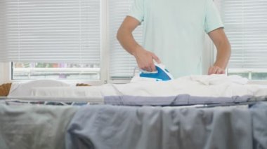 ev işi sırasında Gömlek Ütü kurulu dumanı tüten demir, kullanarak duran genç adam. 4k, ağır çekim