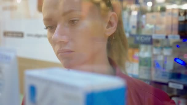 Una mujer mirando una vitrina de cristal en la tienda. 4k, desenfoque de fondo . — Vídeo de stock