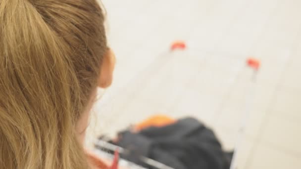 Een vrouw in een supermarkt wordt geconfronteerd door de mand voorbij de tellers. 4k — Stockvideo