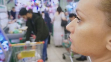 Müşteriler geçen ortasında bir süpermarkette sıkılmış bir kadın portresi. 4 k. bulanıklık