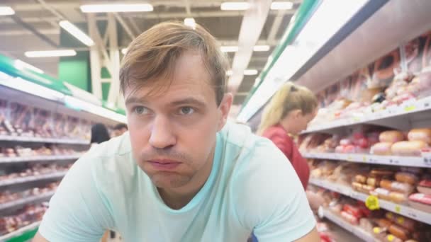 在超级市场, 一个特写的脸的丈夫谁期待他的妻子, 而她在商店购物。厌倦疲倦的丈夫。情侣购物, 4k — 图库视频影像