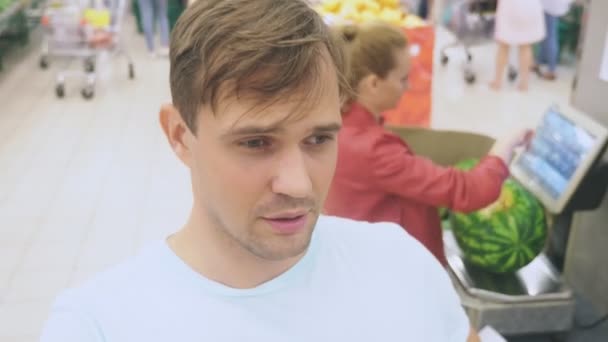 In the supermarket, a close-up of the face of the husband who expects his wife while she is shopping at the store. bored tired husband. couple shopping, 4k — Stock Video