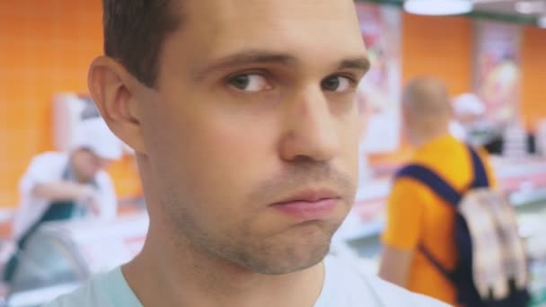 In de supermarkt, een close-up van het gezicht van de man die zijn vrouw verwacht terwijl ze is winkelen bij de store. verveeld moe man. paar winkelen, 4k — Stockvideo
