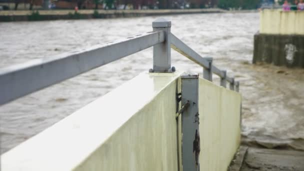 Les eaux grises opaques de la rivière coulent rapidement dans le lit de la rivière par un barrage clôturé dans le centre-ville, Météo pluvieuse, inondation sur le canal, 4k, ralenti — Video