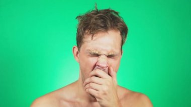 çıplak bir gövde, Uykulu, darmadağınık genç adamla esner ve kameraya doğru görünüyor. 4k, yeşil renkli, ağır çekim. duygular