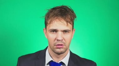 Uykulu, darmadağınık genç adam bir takım elbise ve kravat, esner ve kameraya doğru görünüyor. 4k, yeşil renkli, ağır çekim. duygular