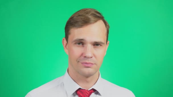 A young man in a shirt and tie on a green background. portrait. emotions and gestures. 4k, close-up. Slow motion. guy looks at camera and cute smile. — Stock Video
