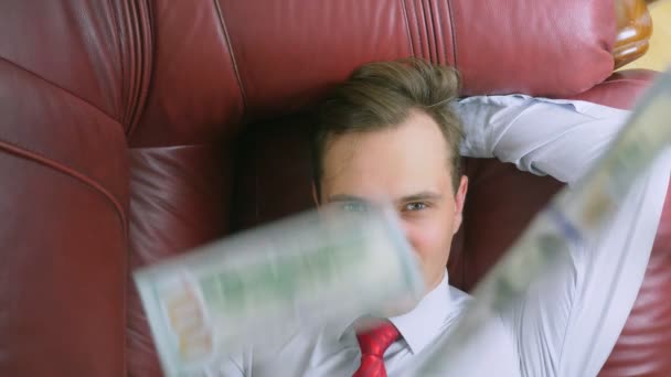 Pojem pasivní příjem. šťastný člověk je ležet na gauči a usmíval se, dolarů mu klesají. 4k, detailní zpomalené — Stock video