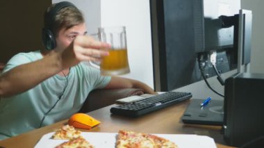 teknoloji, Oyunlar, eğlence, oyun ve insanlar kavramı. evde bir bilgisayar oyunu oynamak, bira içme ve pizza yemek genç bir adam. 4k, ağır çekim