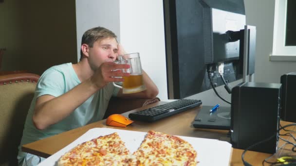 Tecnologia, giochi, intrattenimento, gioco e concetto di persone. un giovane che gioca a un gioco per computer a casa, beve birra e mangia pizza. 4k, rallentatore — Video Stock