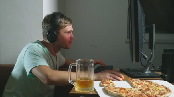 Technologie, Spiele, Unterhaltung, Spiel und Menschen-Konzept. Ein junger Mann spielt zu Hause ein Computerspiel, trinkt Bier und isst Pizza. 4k, Zeitlupe — Stockvideo