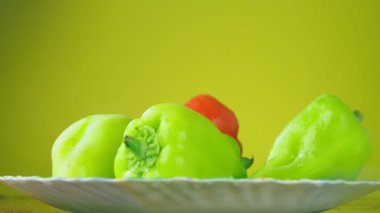 Taze Balgar biber tabağa su ile düşer. Beslenme kavramı. Sarı bir arka plan üzerinde ayrı tut yavaşlama.