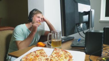Tok bir adam evde kanepede oturuyor, içecekler bira ve pizza, bir bilgisayarda Internet kullanımı, çevrimiçi bir film seyrederken veya bağımsız bir serbest yazar olarak çalışan yiyor. 4k, ağır çekim