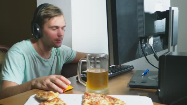 Teknik, spel, underhållning, lek och människor koncept. en ung man spelar ett datorspel hemma och dricka öl och äta pizza. 4k, Slowmotion — Stockvideo