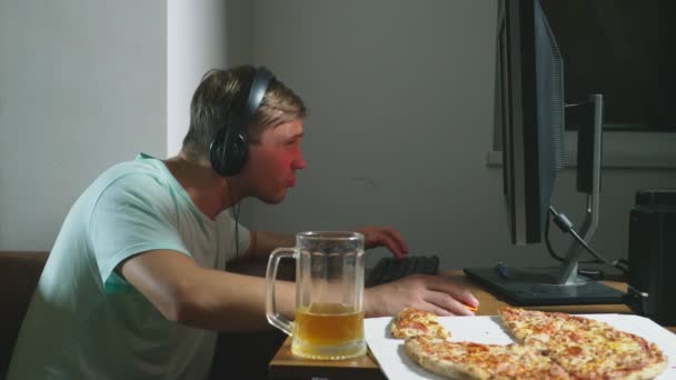 technology, games, entertainment, play and people concept. a young man playing a computer game at home, drinking beer and eating pizza. 4k, slow motion