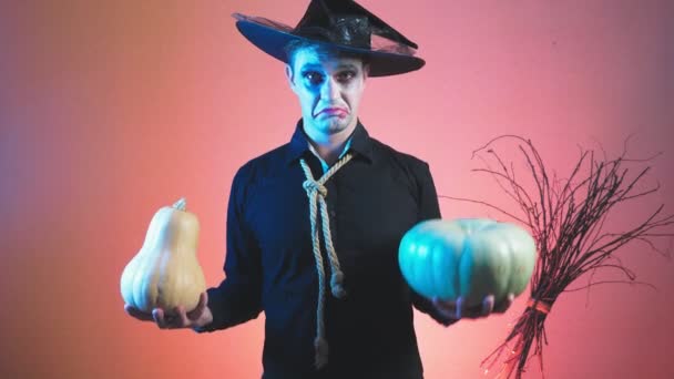 Jonge man in een zombie kostuum voor halloween, met pompoenen in zijn handen. 4k, slow-motion. Close-up — Stockvideo
