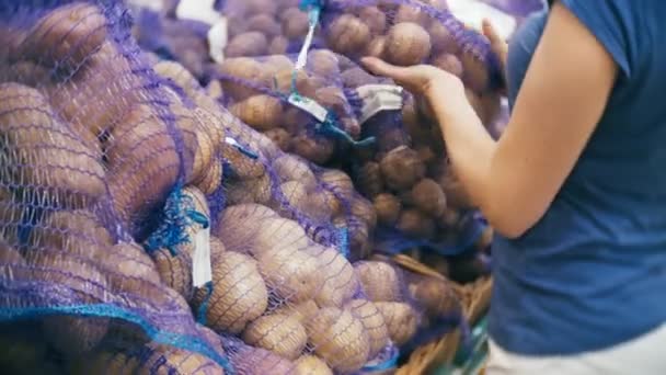 Eine Frau im Supermarkt kauft Gemüse, Kartoffeln. — Stockvideo