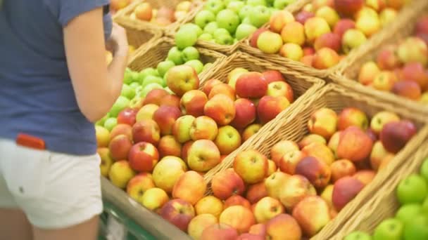 Mujer joven eligiendo manzana en el mercado de supermercados de frutas y verduras. 4k — Vídeo de stock