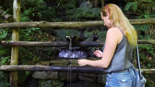 Kvinna kurvorna att släcka sin törst. Dricksvatten från berget. ren källa. 4k, Slowmotion — Stockvideo