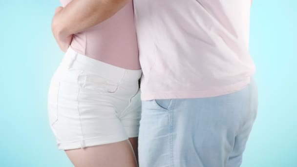 Κοντινό πλάνο. τα ισχία. Μόδα εικόνα του ένα νεαρό ζευγάρι σέξι, αγκαλιές στο ανοιχτό μπλε φόντο, 4k, αργή κίνηση — Αρχείο Βίντεο