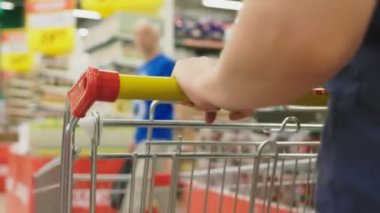 Bir kadın bir süpermarkette sepet sayaçları geçmiş tarafından geçiyor. 4k, yakın çekim, bir kadın süpermarket yürür..