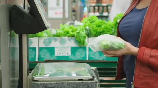 Uma mulher num supermercado a comprar vegetais. pepinos e tomates, pesando em escalas. self-service. 4k — Vídeo de Stock