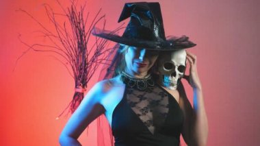 güzel genç seksi kadın kara cadı kostüm ve şapka, bir süpürge ve onun elinde bir kafatası. kopya alanı. 4k, ağır çekim