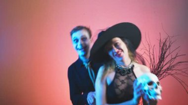 güzel bir çift, bir erkek ve bir kadın için Cadılar Bayramı, cadı ve zombi kostümleri 4k, yavaş hareket, kafatası ellerini tutun. kutlama tatil,