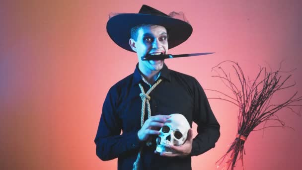 Ein junger Mann in einem Zombie-Kostüm zu Halloween, mit einem Totenkopf in den Händen. 4k, Zeitlupe. Nahaufnahme — Stockvideo